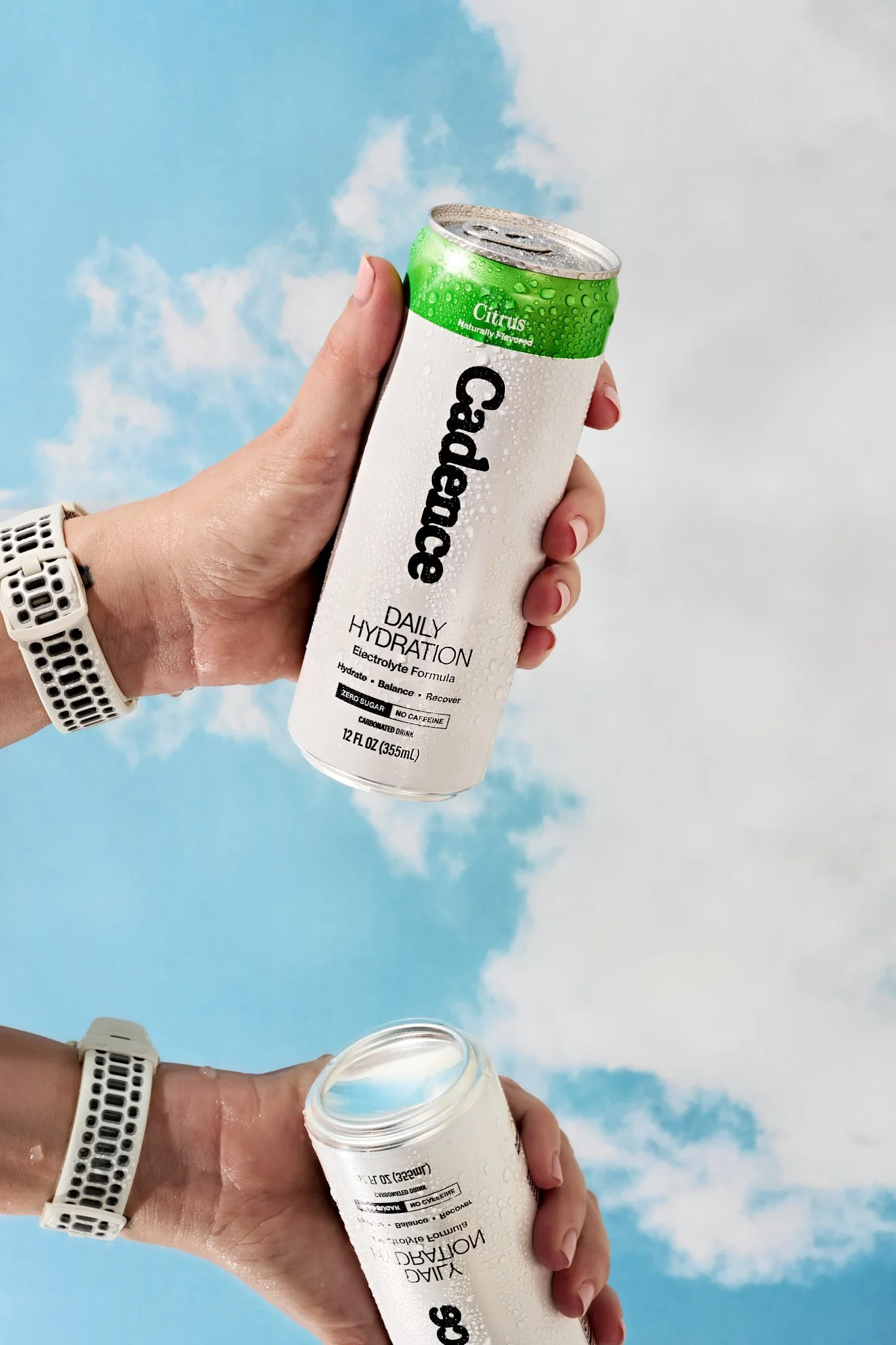 Close-up of a hand holding a can of Topo Chico hard seltzer with a blue sky and clouds in the background, condensation on the can. Orlando commercial food and beverage photographer specializing in CPG brands