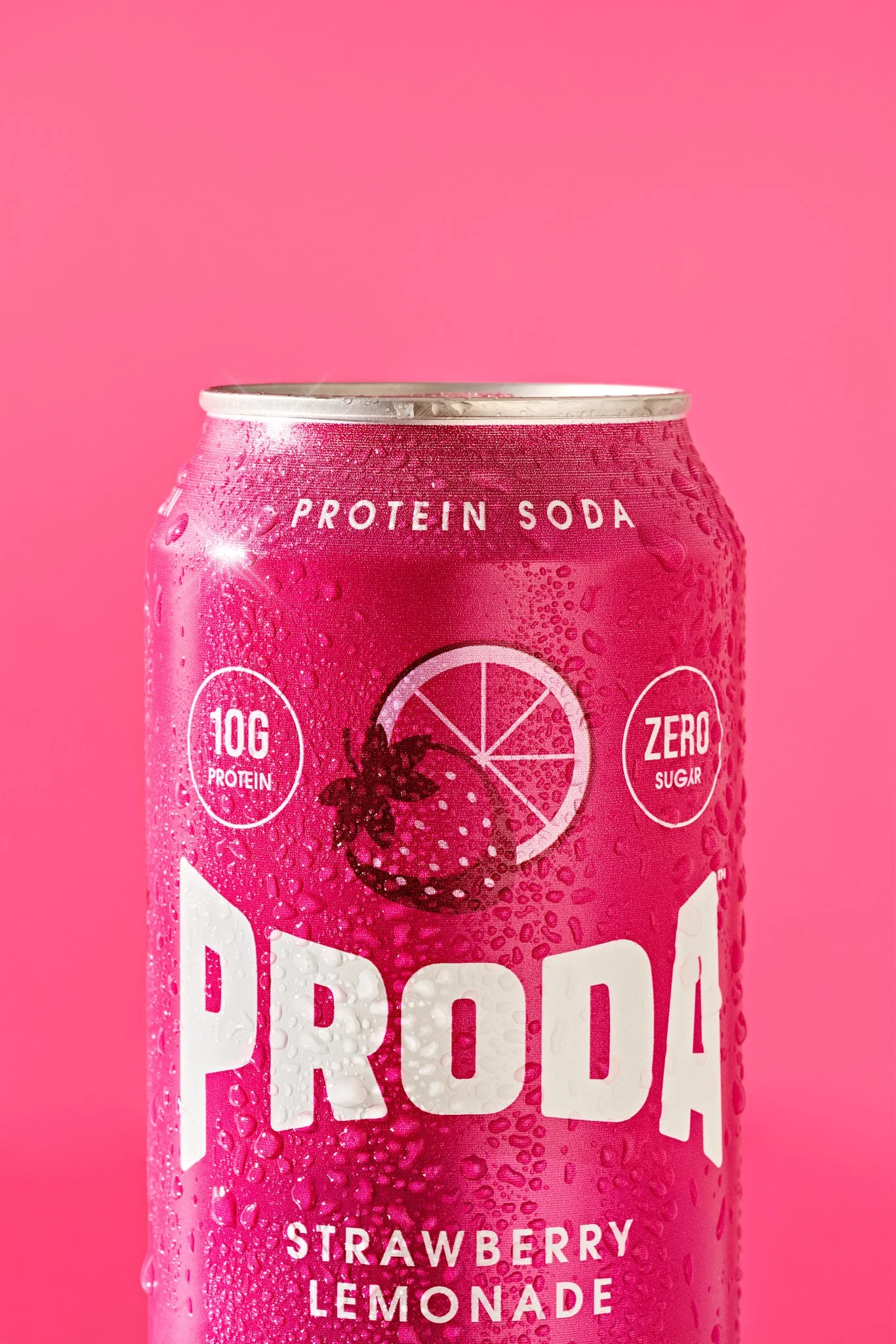Close-up of a pink can of strawberry lemonade drink with droplets of water on its surface, against a pink background. Commercial product photography for a modern beauty and wellness brand