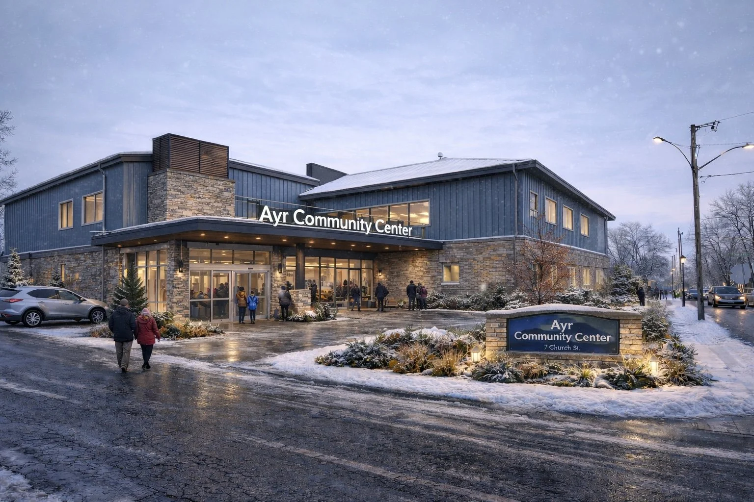 The Ayr Community Center seen on a winter evening, with snow on the ground and people entering the building through glass doors, illuminated by warm lights.