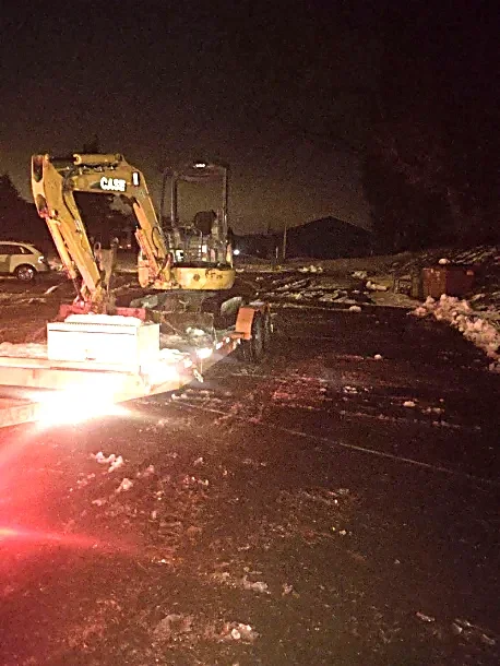 Nighttime scene with construction equipment and snow on the ground, no people visible.