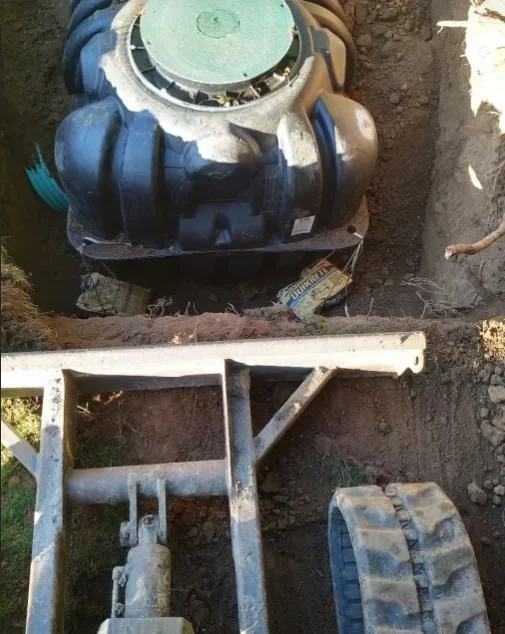 An underground water pump installed in a trench with a hand truck nearby.