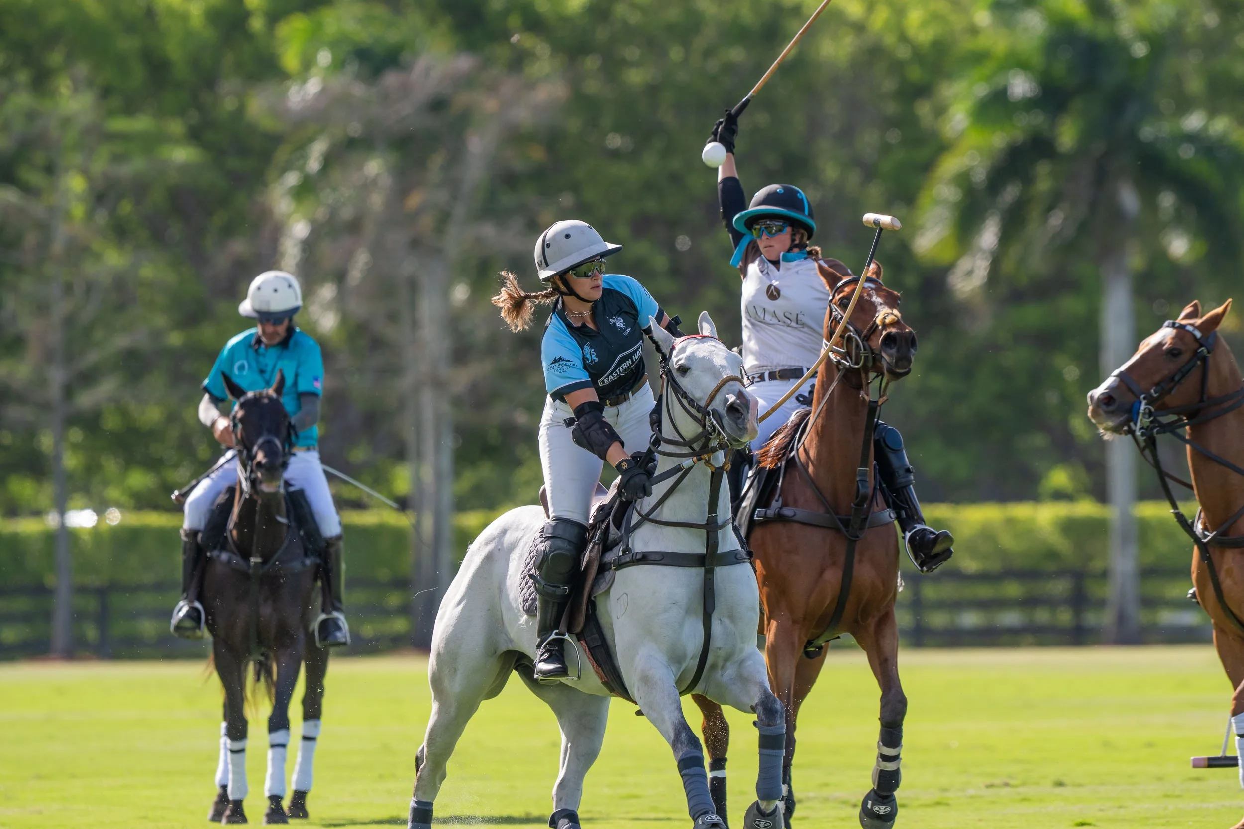 Lacrosse players riding horses on a grassy field during a game.