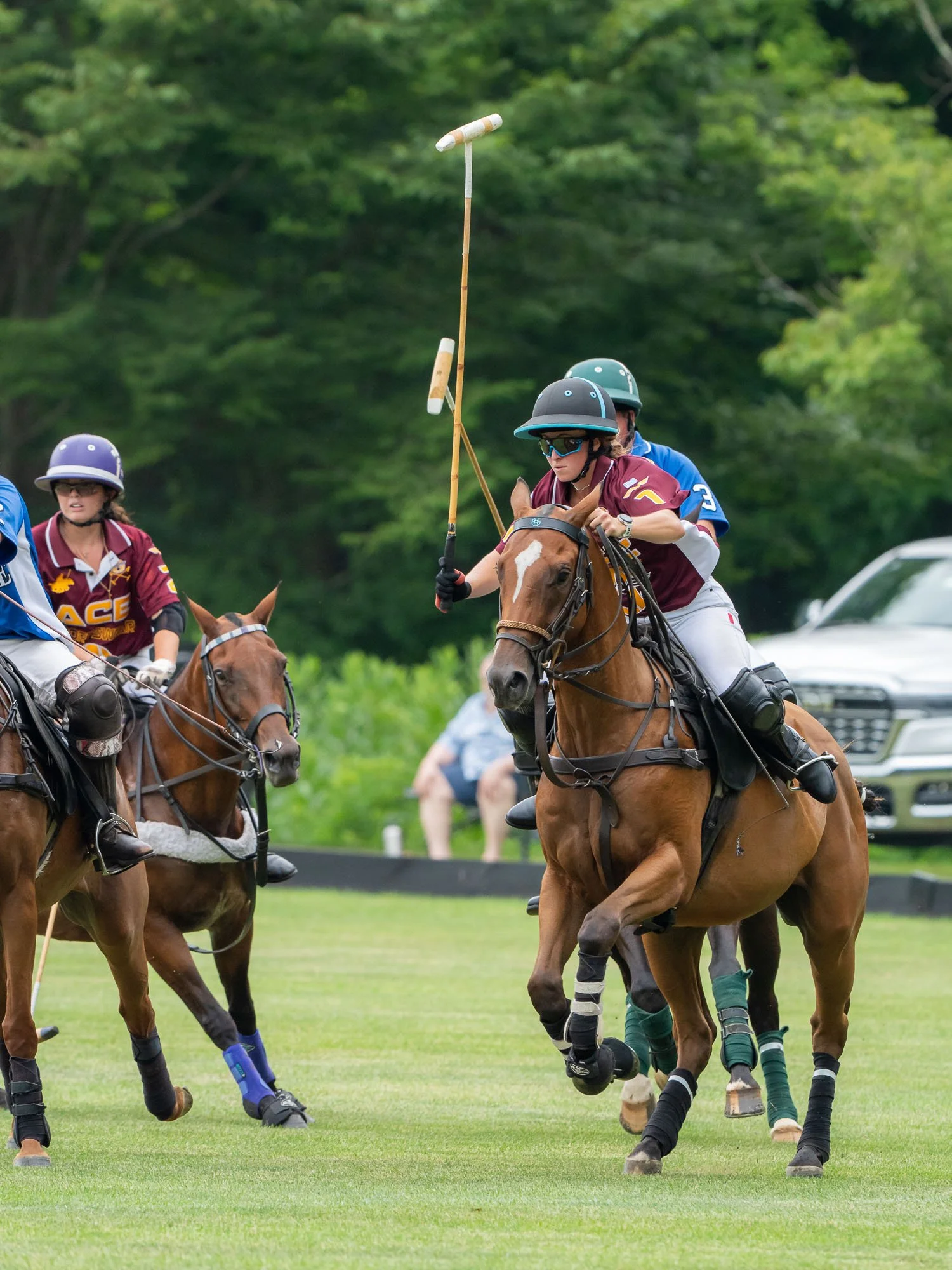 Polo players riding horses during a match on a grassy field.