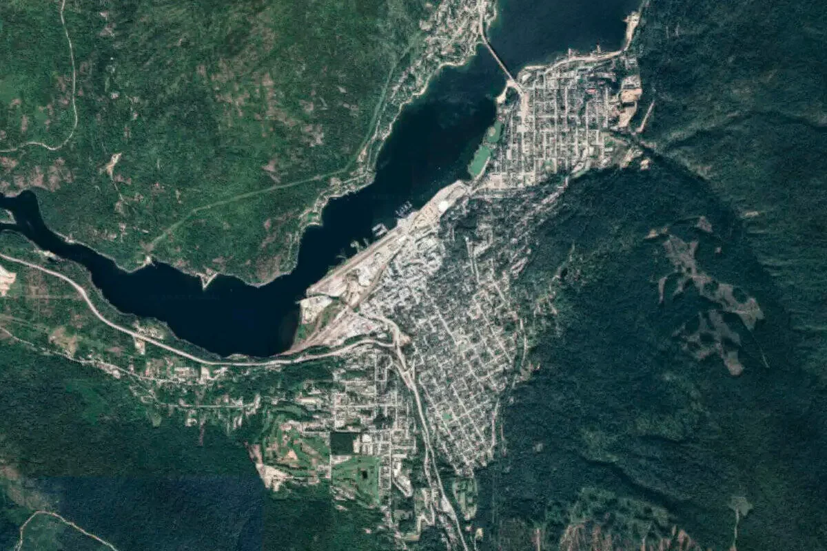 Aerial view of a town surrounded by forests, a large body of water, and mountains