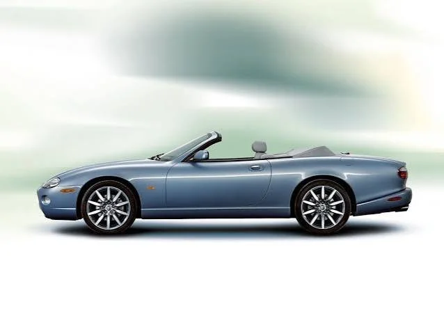 A blue convertible sports car with the top down, set against a blurred background.