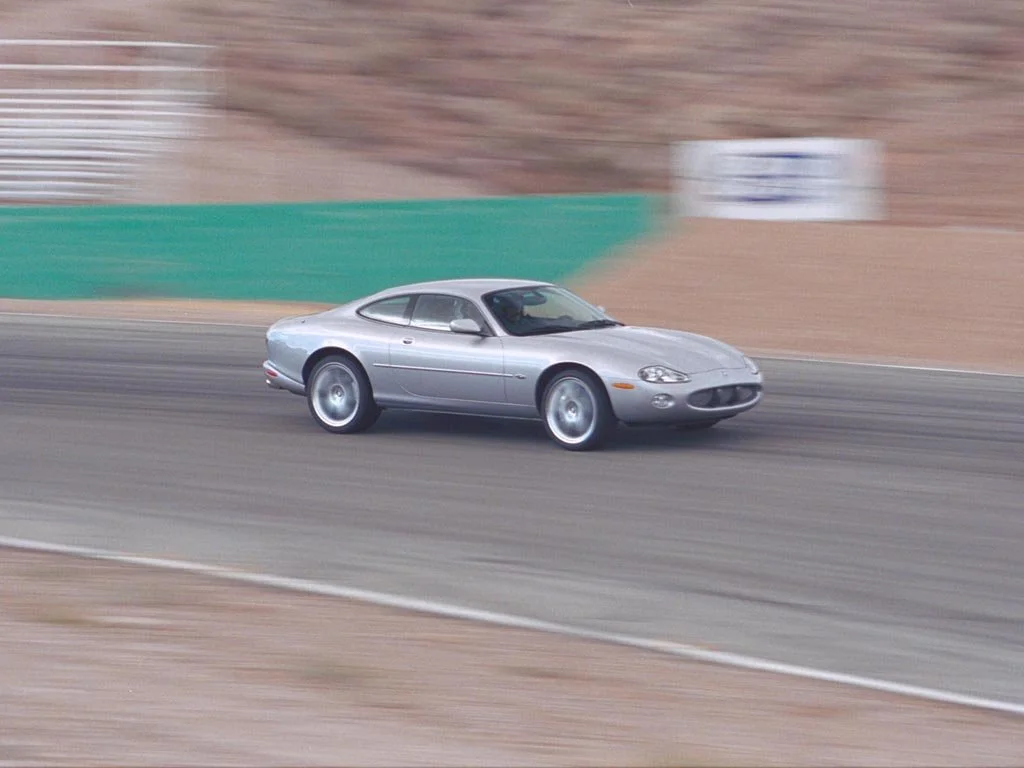 A silver sports car on a racetrack with a blurred background.