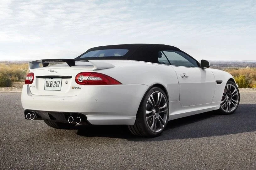White convertible car with black roof parked on an open road.