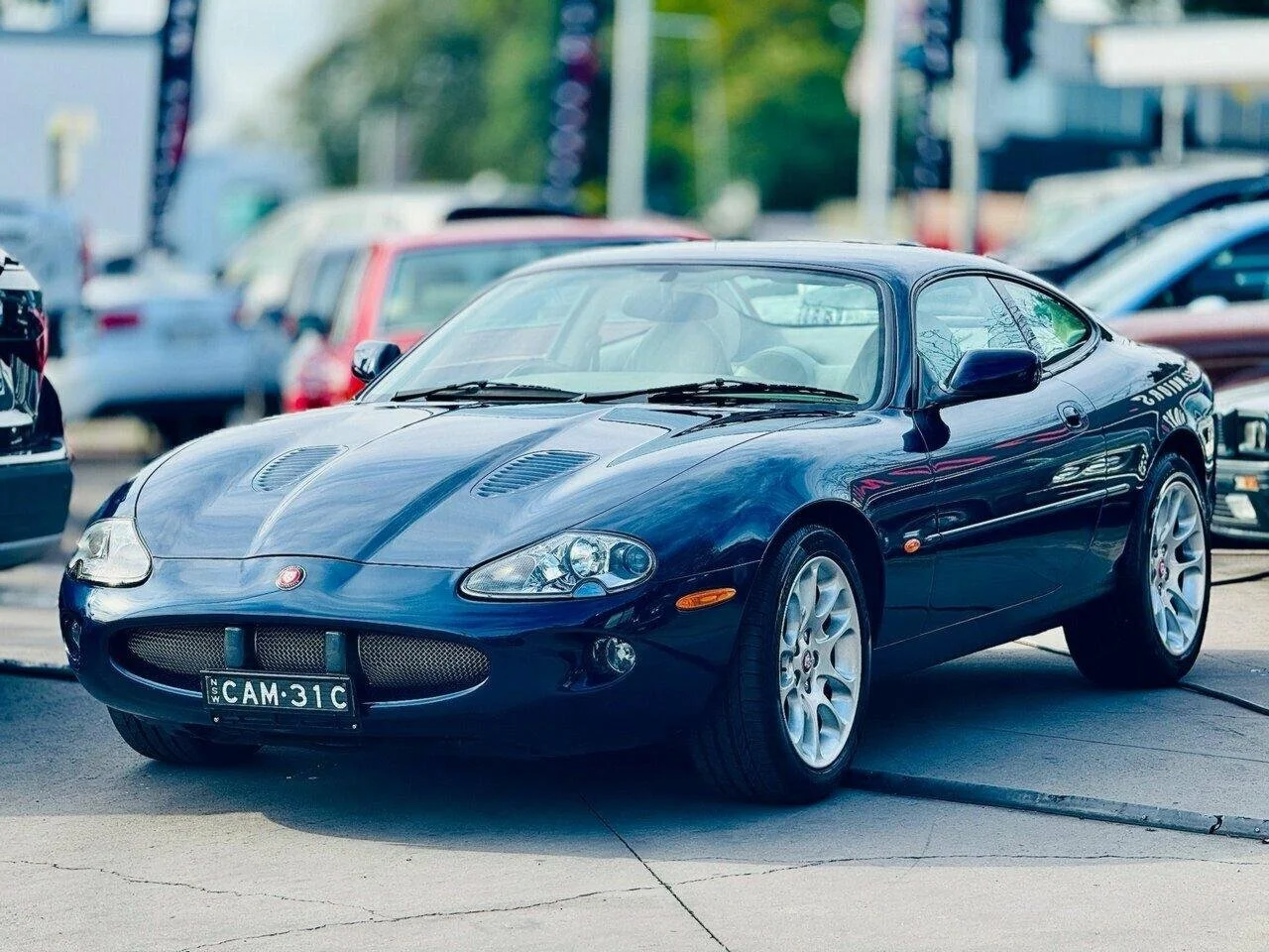 A black Ford Puma sports car parked in a lot with other vehicles in the background.