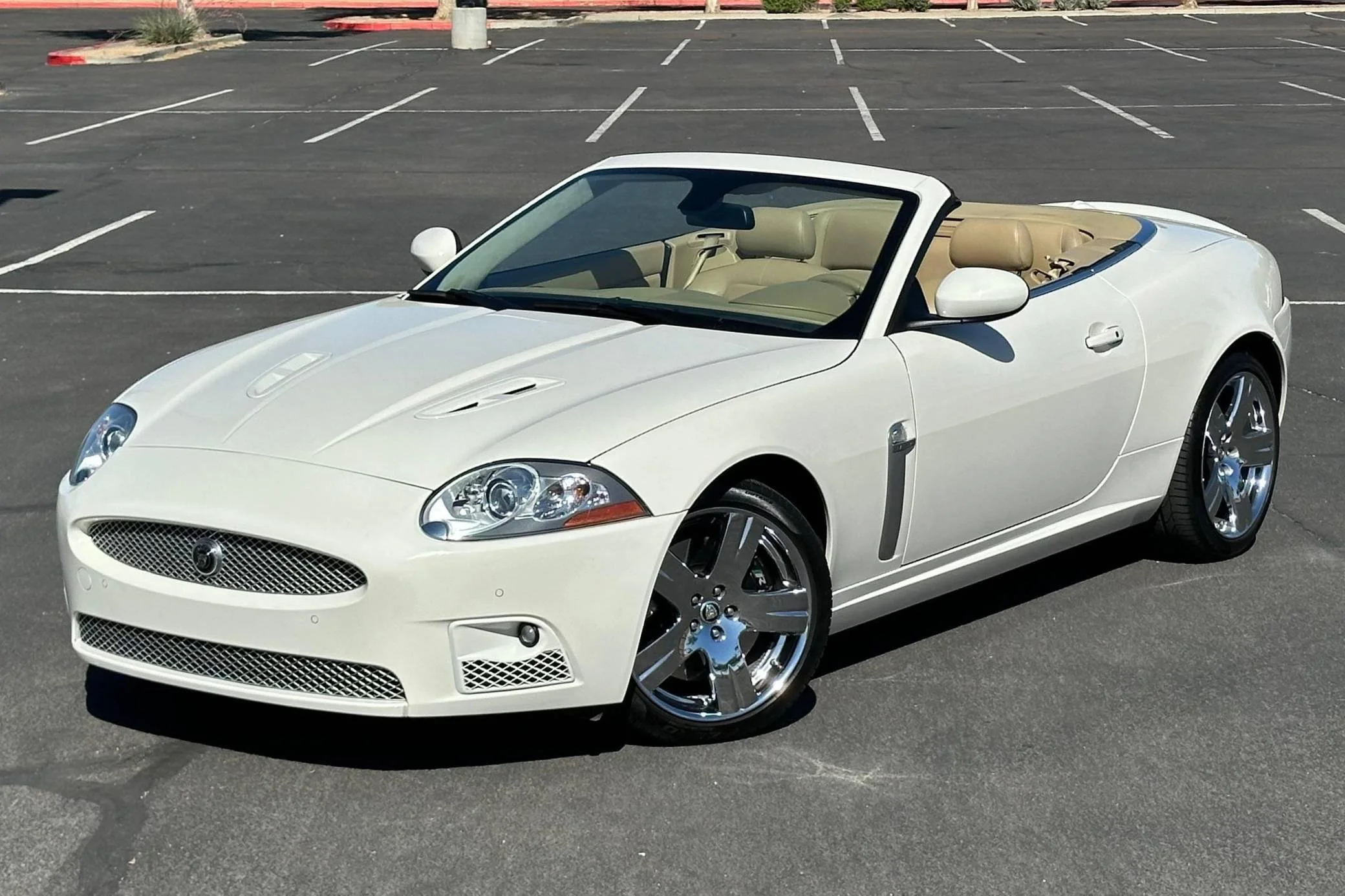 A white convertible sports car parked in an empty parking lot.