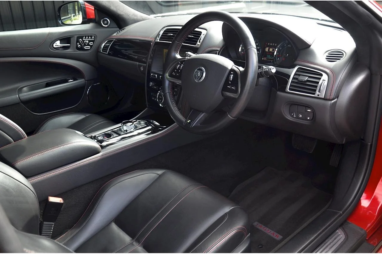 Interior of a modern car showing the driver's seat, steering wheel, dashboard, and center console with gear shifter and control buttons.