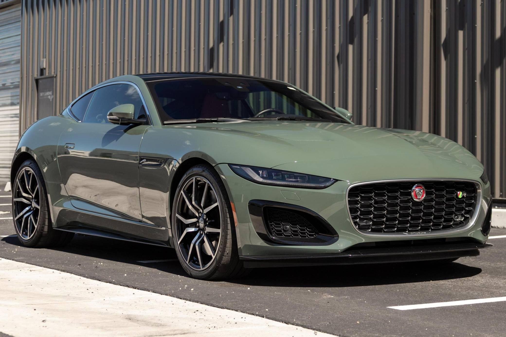 A green sports car parked in a parking lot with a modern metal building in the background.