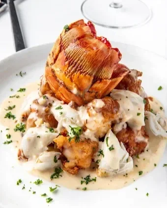Baked ham served with mashed potatoes and gravy, garnished with parsley.