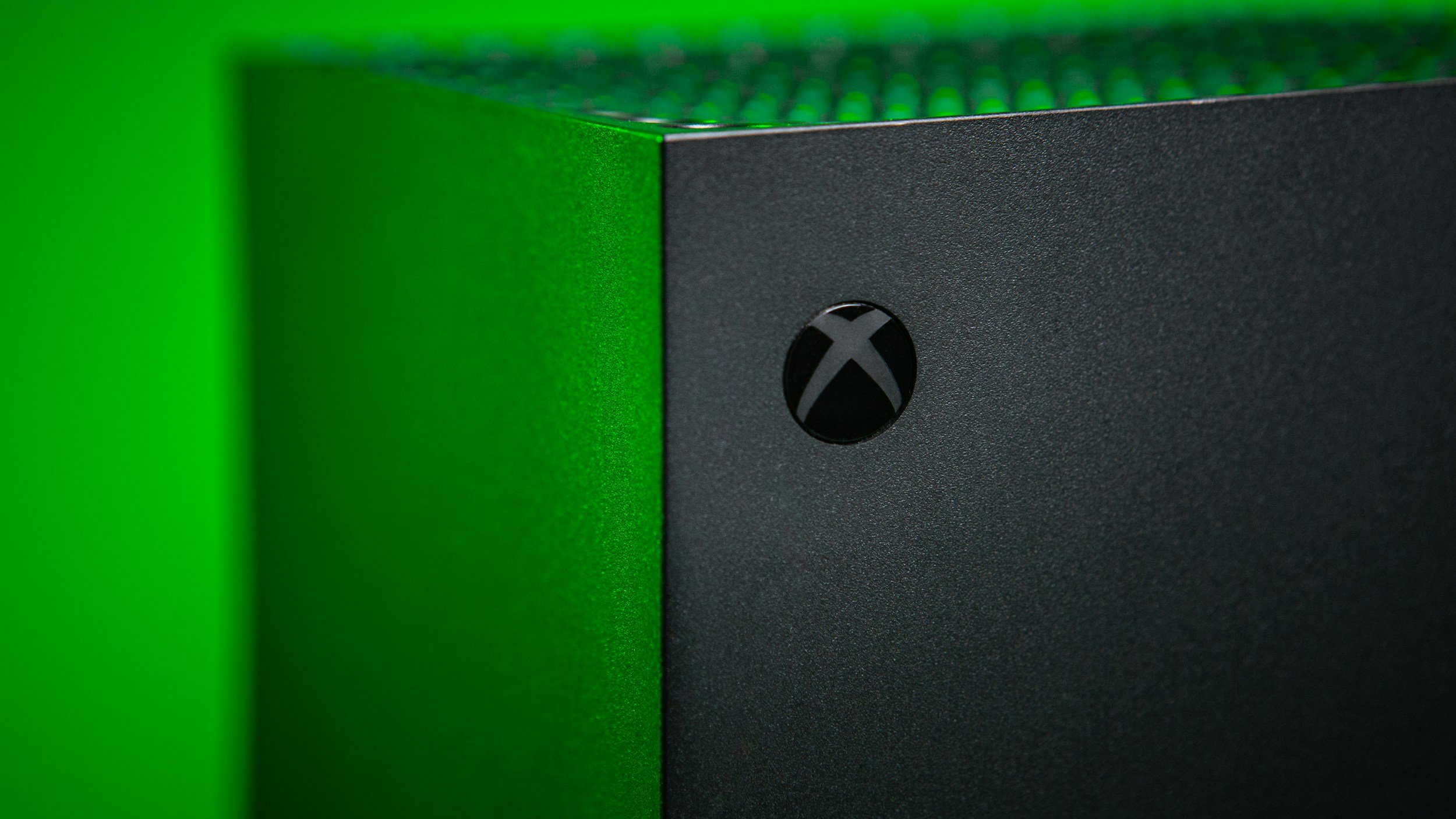 Close-up of a black Xbox Series X gaming console with a green accent in the background.