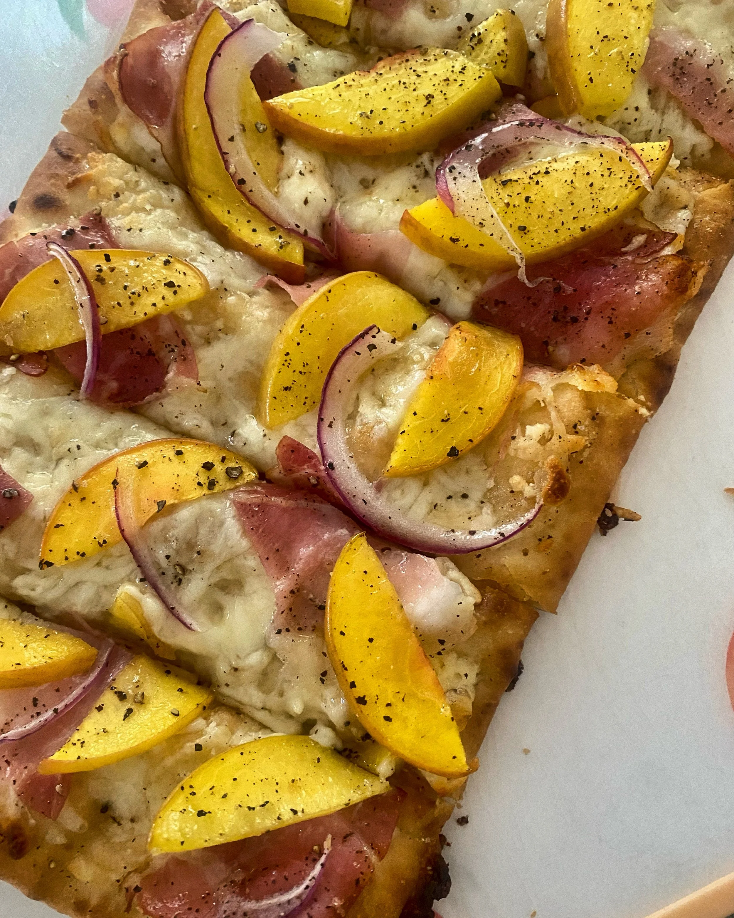 Grilled peach flatbread rubbed in garlic butter, topped with red onion, crispy prosciutto, fontina cheese, black pepper and drizzled with a mango dijon sauce