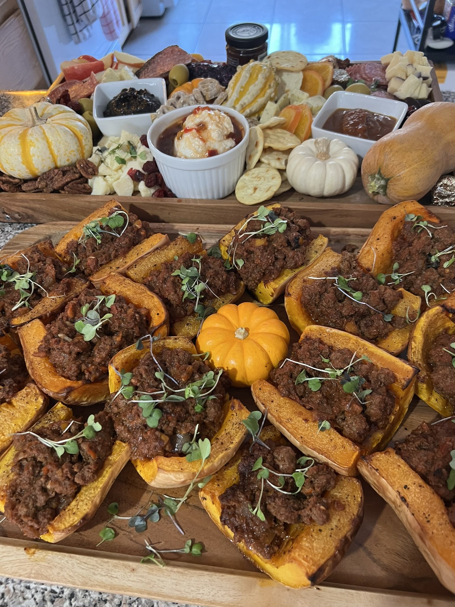 Sweet stuffed squash with ground beef on a wooden board, garnished with microgreens.