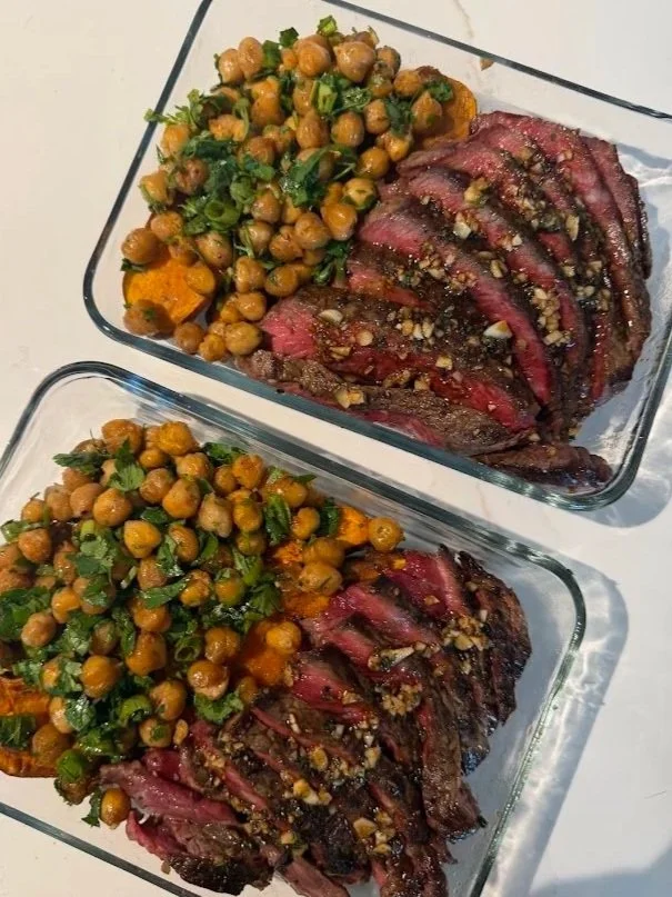 Two glass dishes with sliced medium-rare steak topped with Moroccan oil, served with roasted chickpeas over roasted sweet potato.