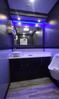 Modern bathroom featuring a white sink, a black vanity, a large mirror, and a bathtub, with blue LED lighting.