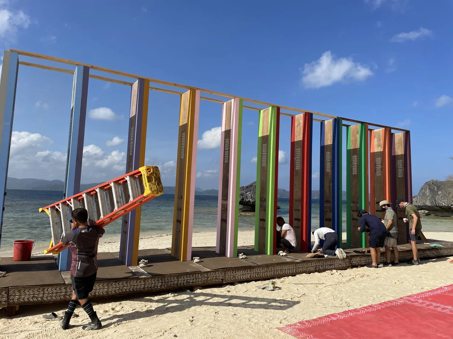 Crew building a colourful challenge structure on a beach