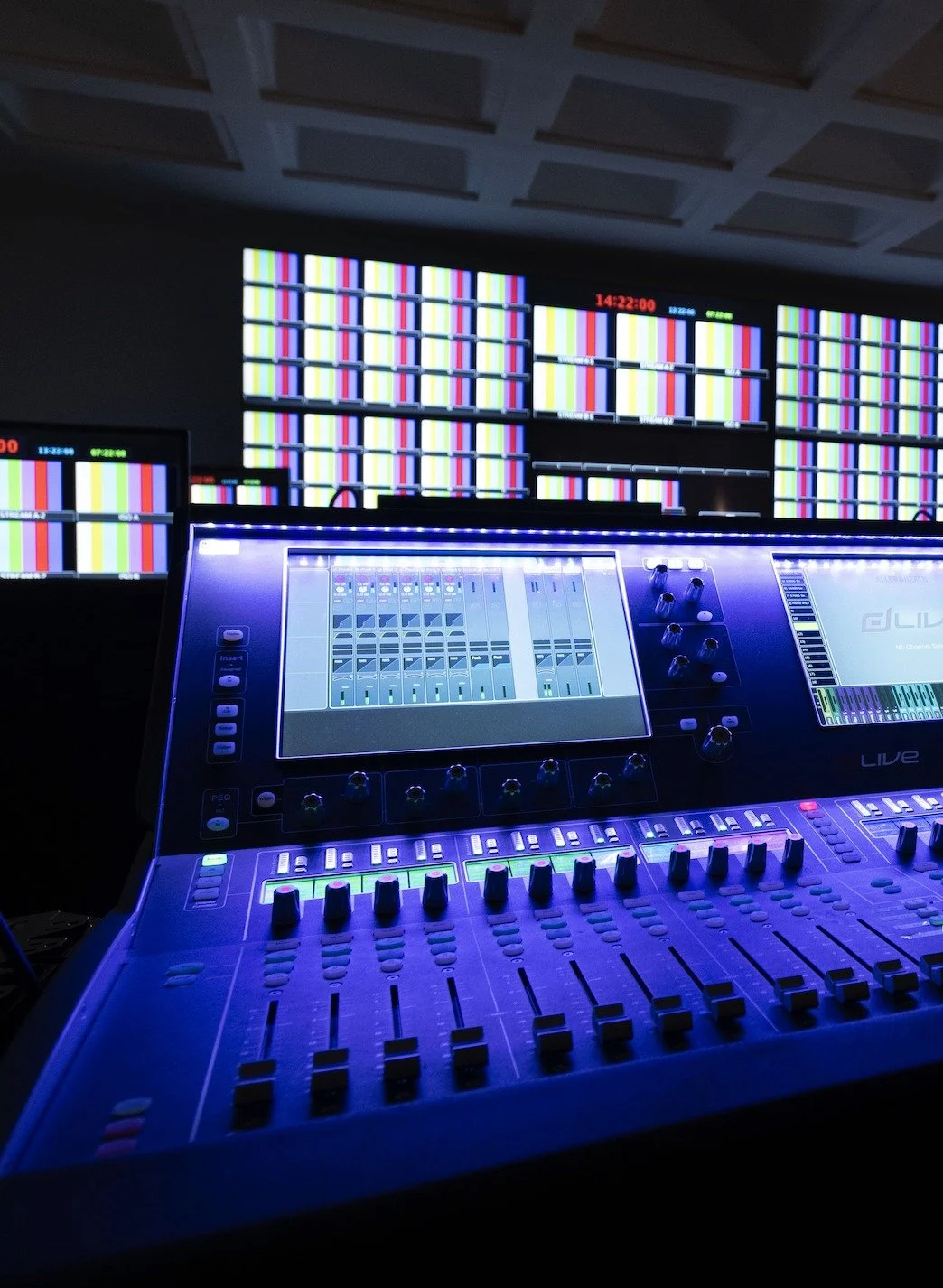 Audio mixing console in front of a multiview monitor wall