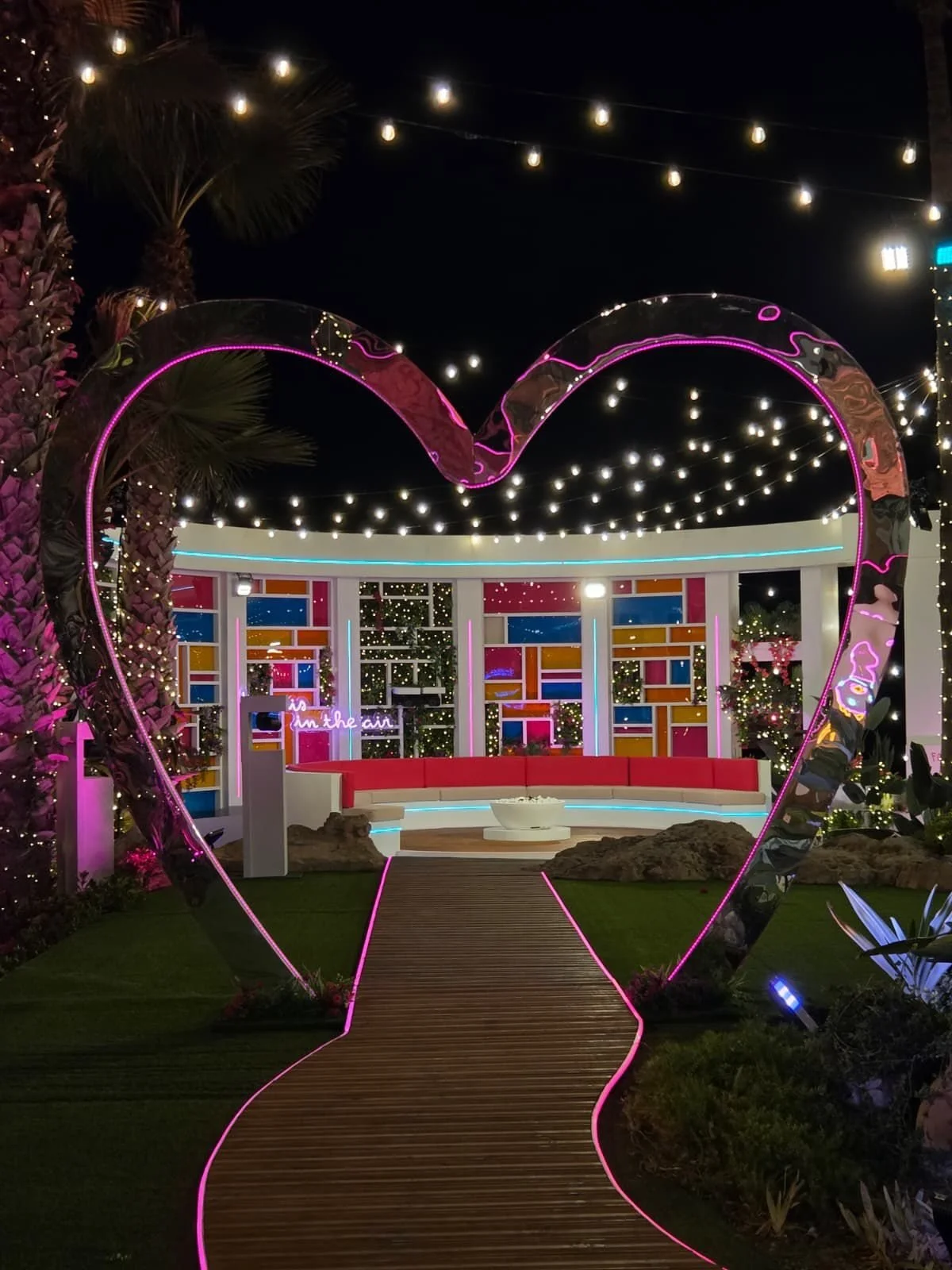 Heart-shaped neon arch over a lit walkway