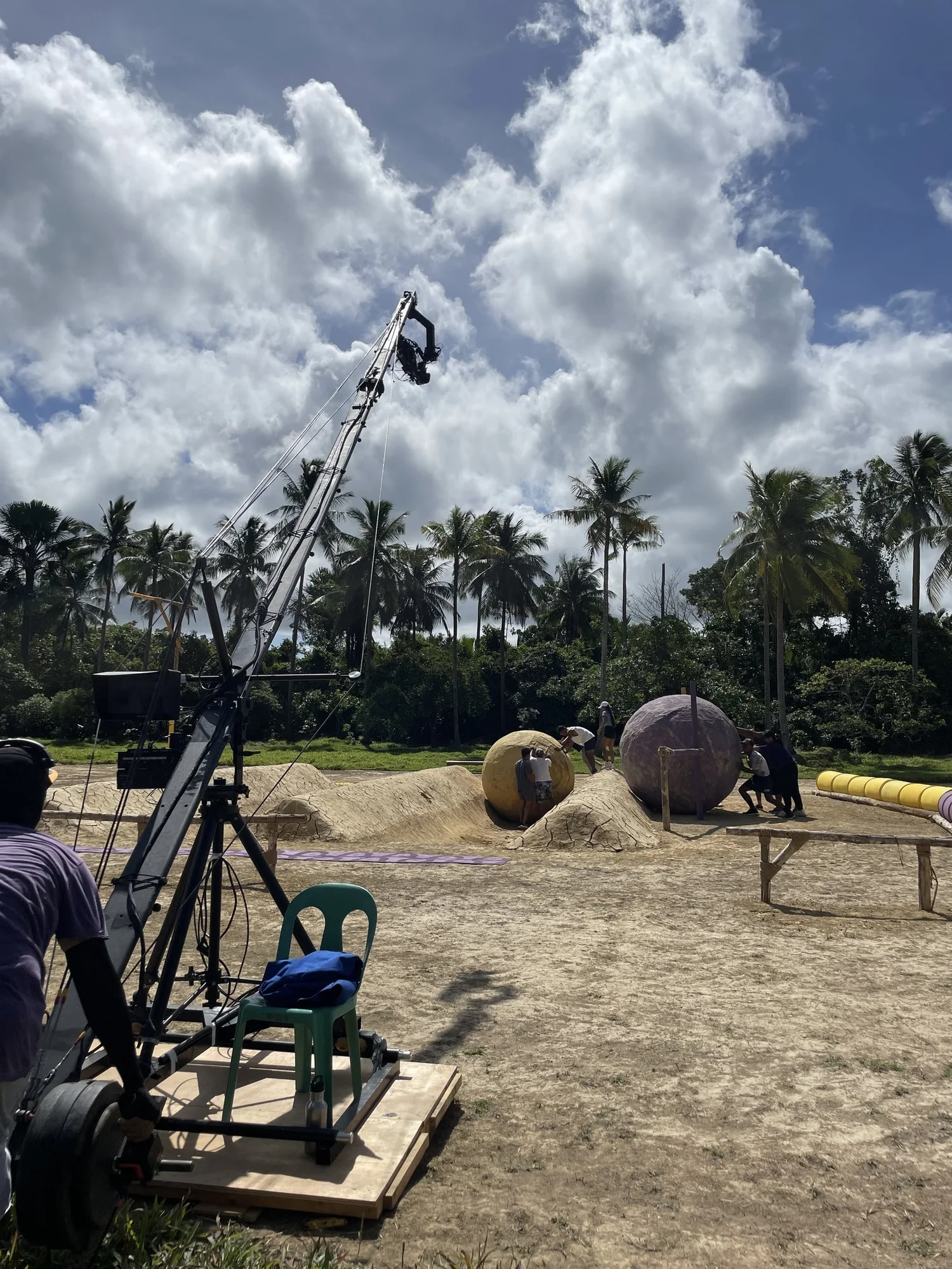 Camera crane filming a challenge set among palm trees