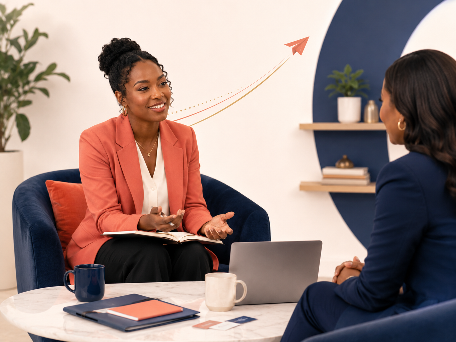 Two women having a conversation in an office setting. One woman is wearing a salmon blazer and is holding a notebook, while the other woman is dressed in a navy blazer. There is a laptop, coffee cups, and notebooks on the table, and a graphic of an upward arrow with a paper airplane on the wall behind them.