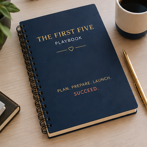 A blue spiral notebook titled "The First Five Playbook" with a subtitle "Plan. Prepare. Launch. Succeed." on a wooden desk, accompanied by a gold pen, a cup of black coffee, and part of a potted plant.