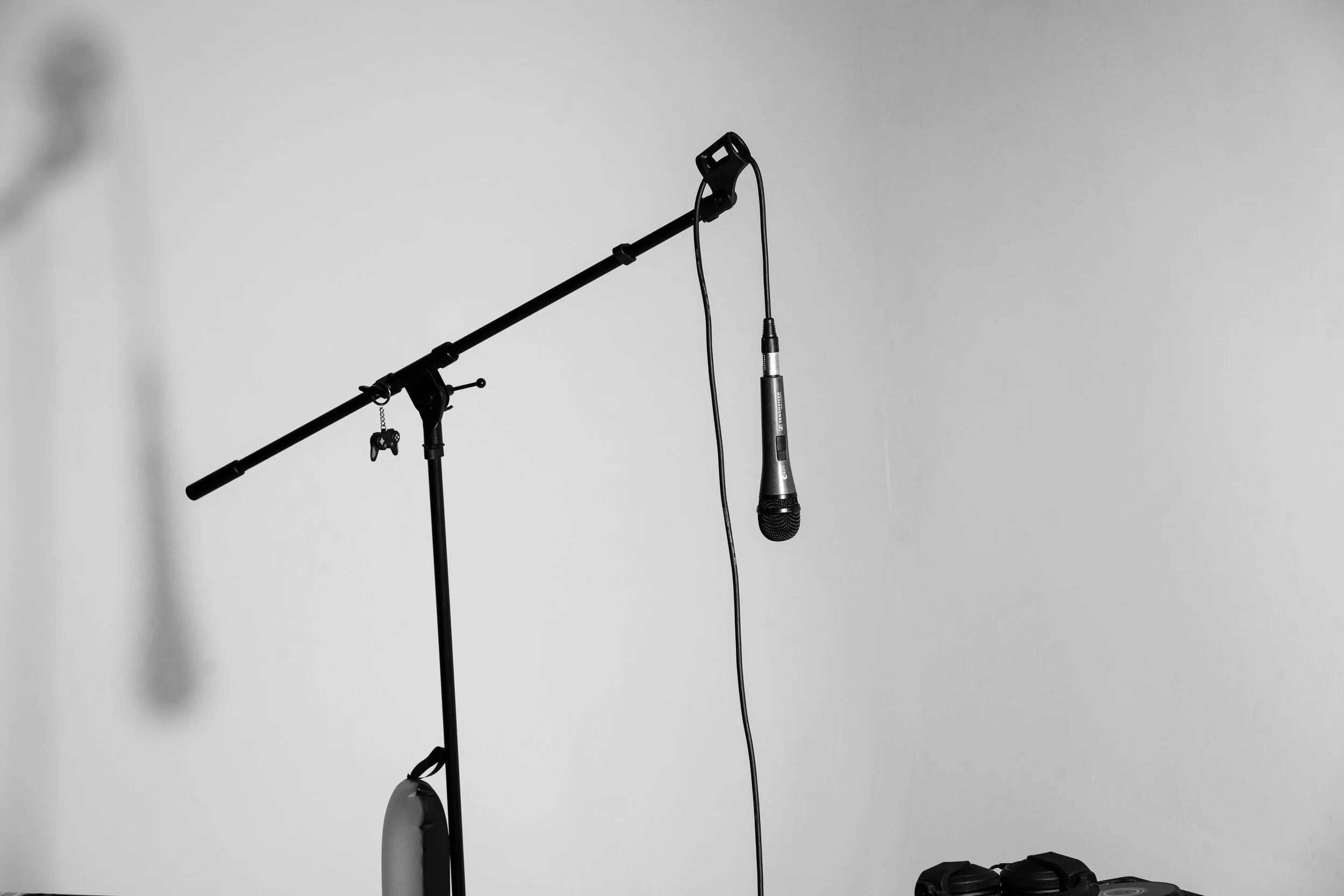 A microphone connected to a stand, with a wired microphone hanging down, placed against a plain white background.