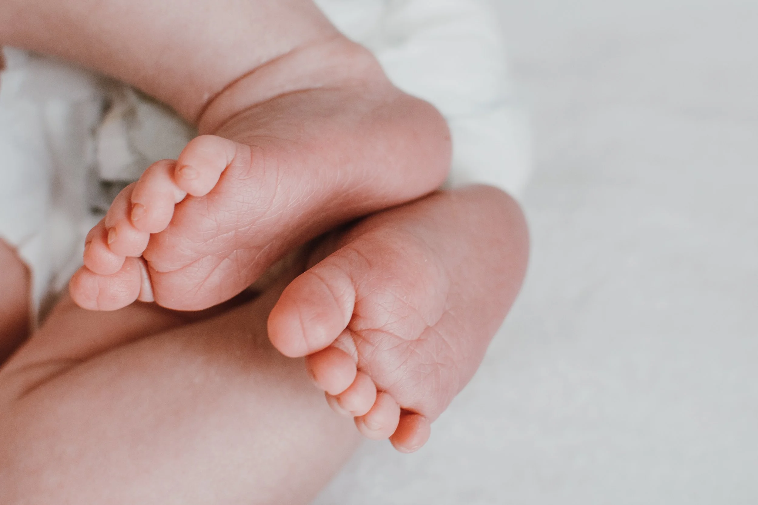 Close-up of a tiny baby foot being held gently by an adult hand.