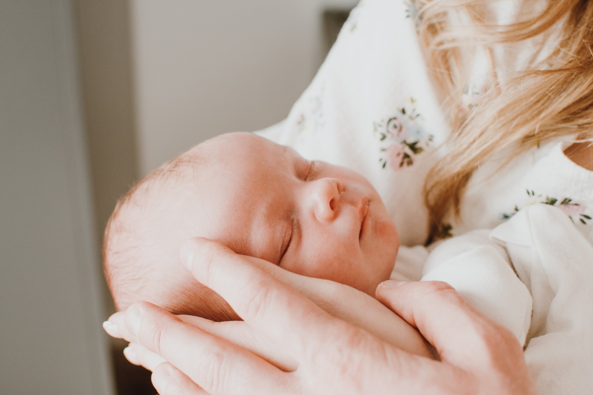 A person holding a sleeping newborn baby close to their face.