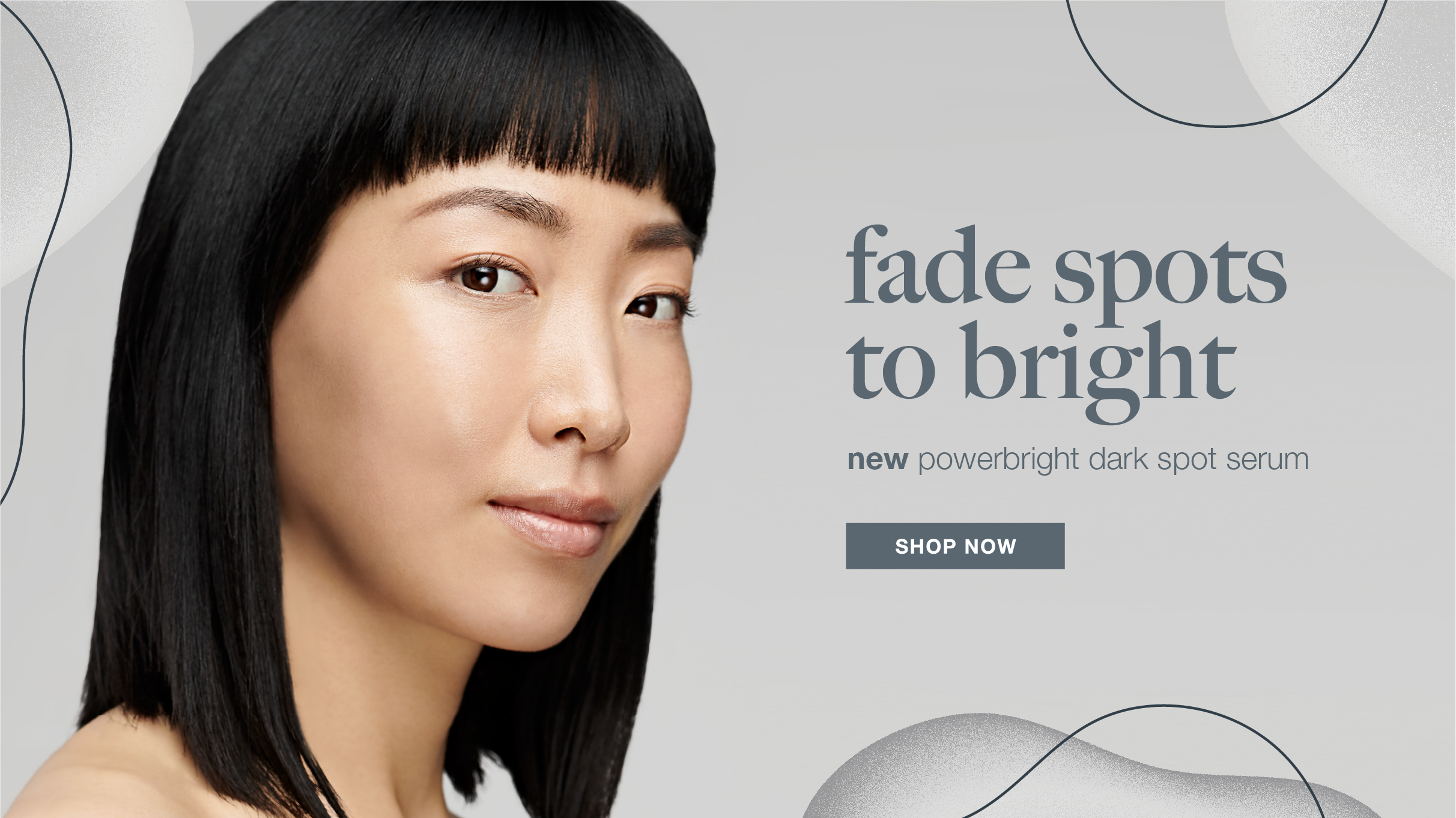 Close-up of a woman with straight black hair and bangs, looking directly at the camera, promoting a dark spot serum to fade spots and brighten skin.