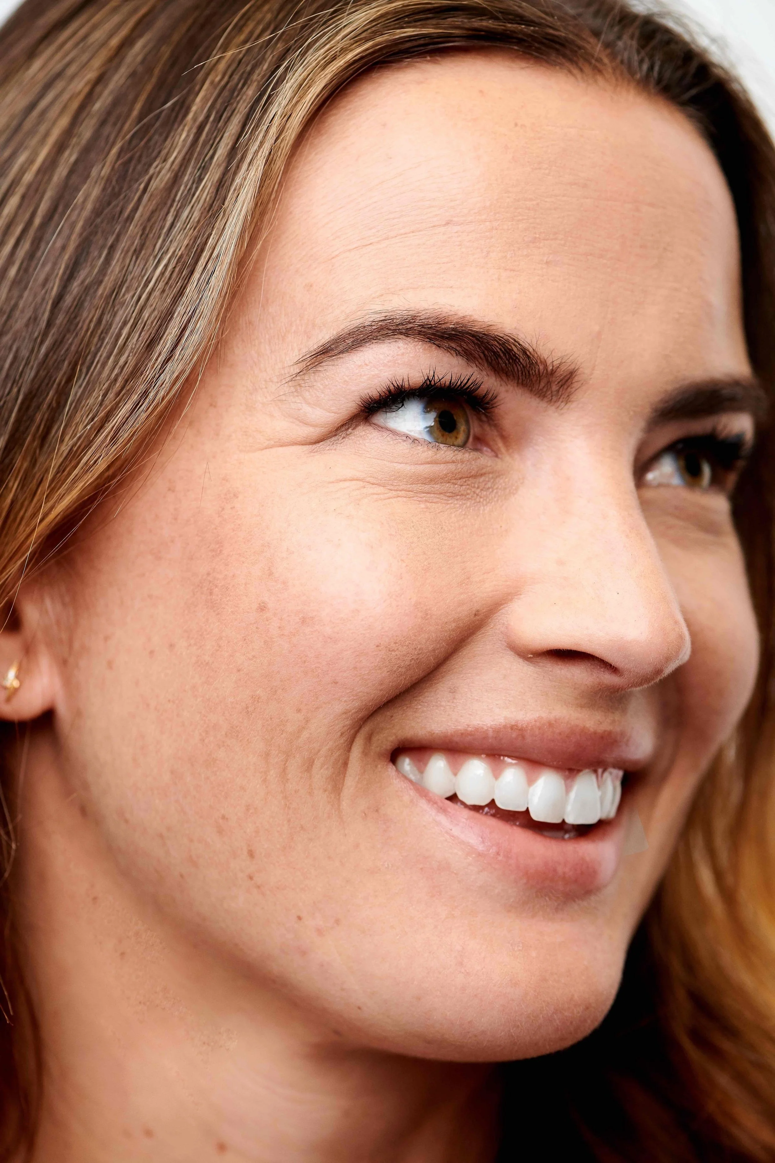 Close-up of a smiling woman's face focusing on her smile, eyes, and hair.