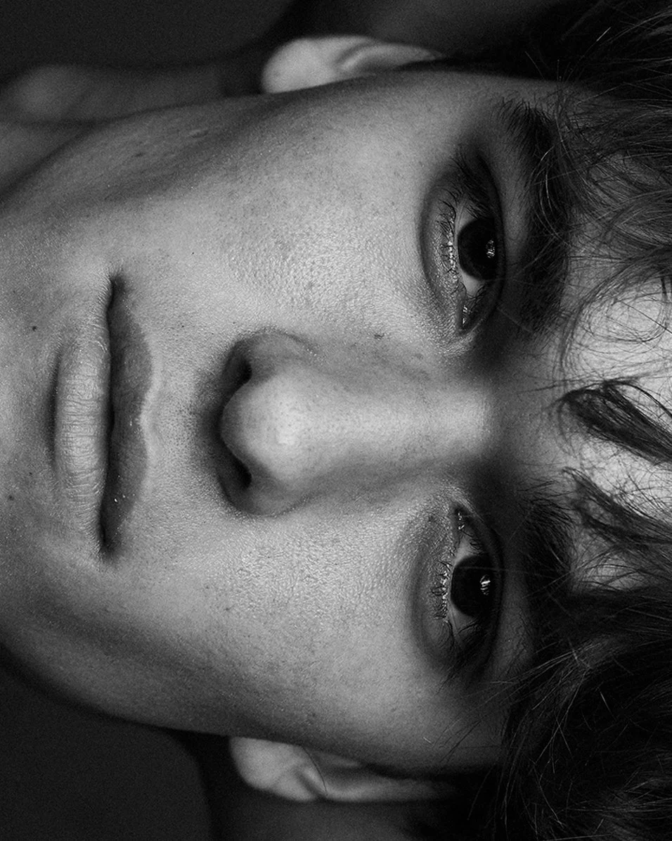 Black-and-white beauty close-up of a face turned sideways, skin texture and freckles left visible.