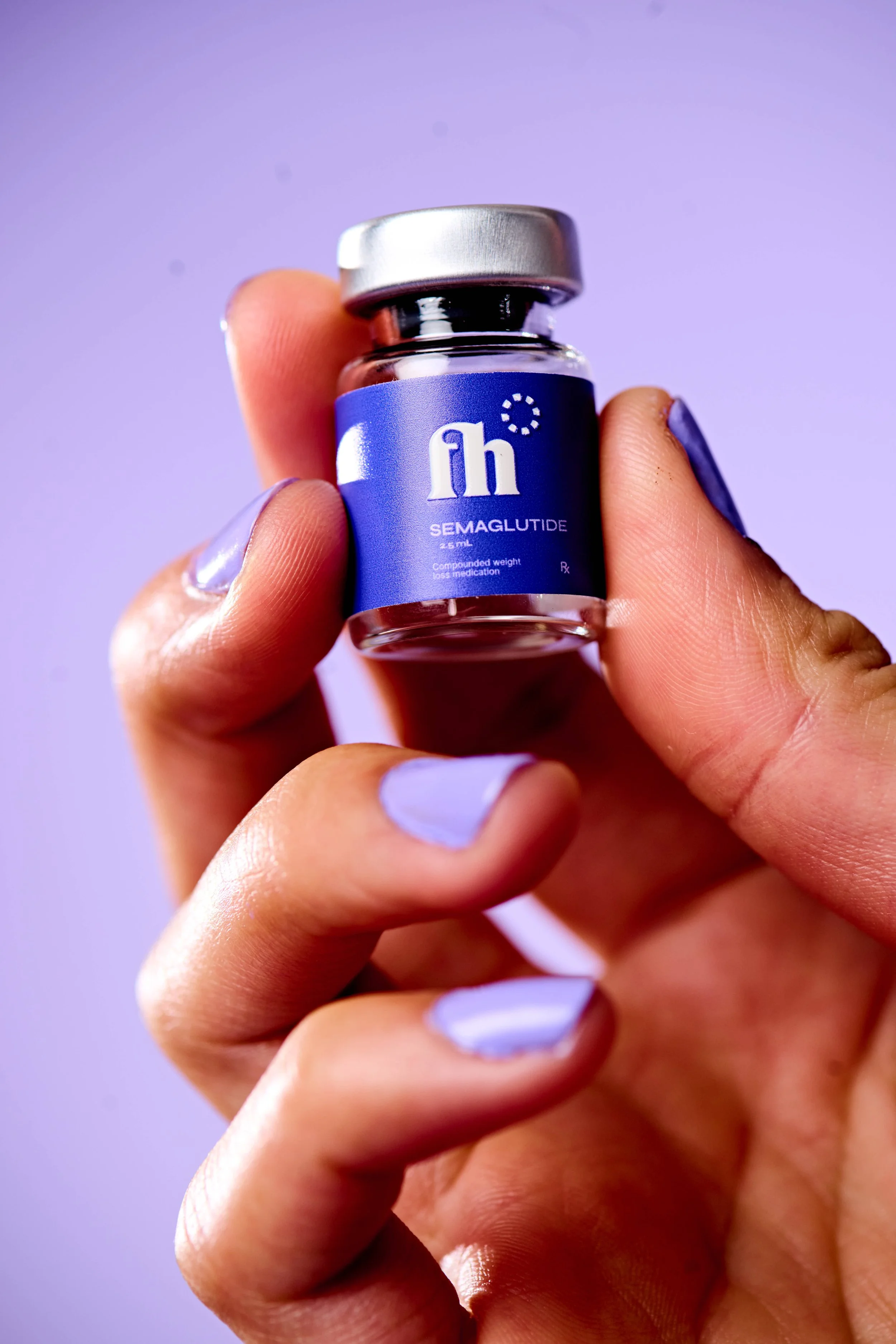 Product-in-hand shot of a FuturHealth vial held against a lilac background with matching nails.