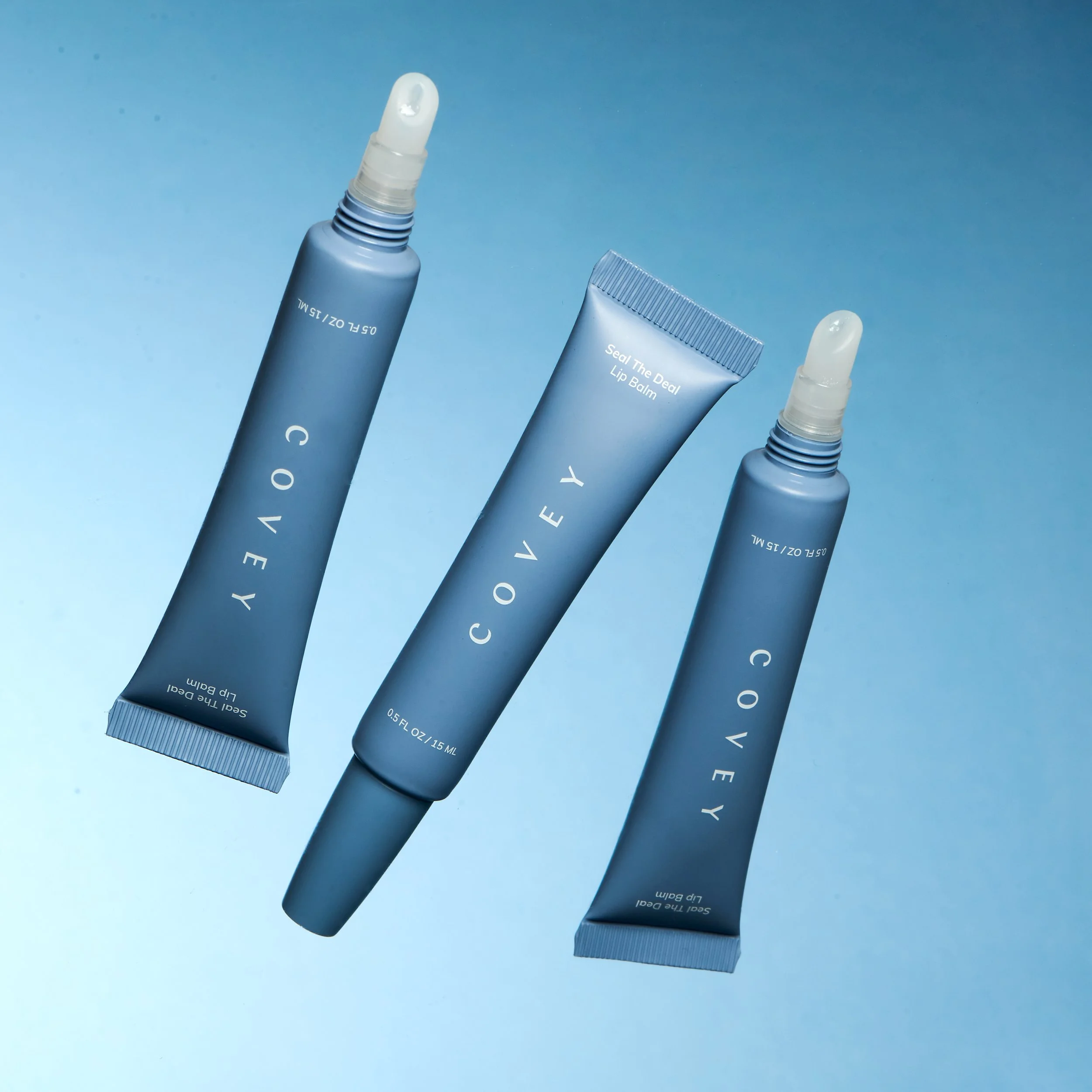 E-commerce still life of three Covey skincare tubes arranged on a pale blue gradient set.