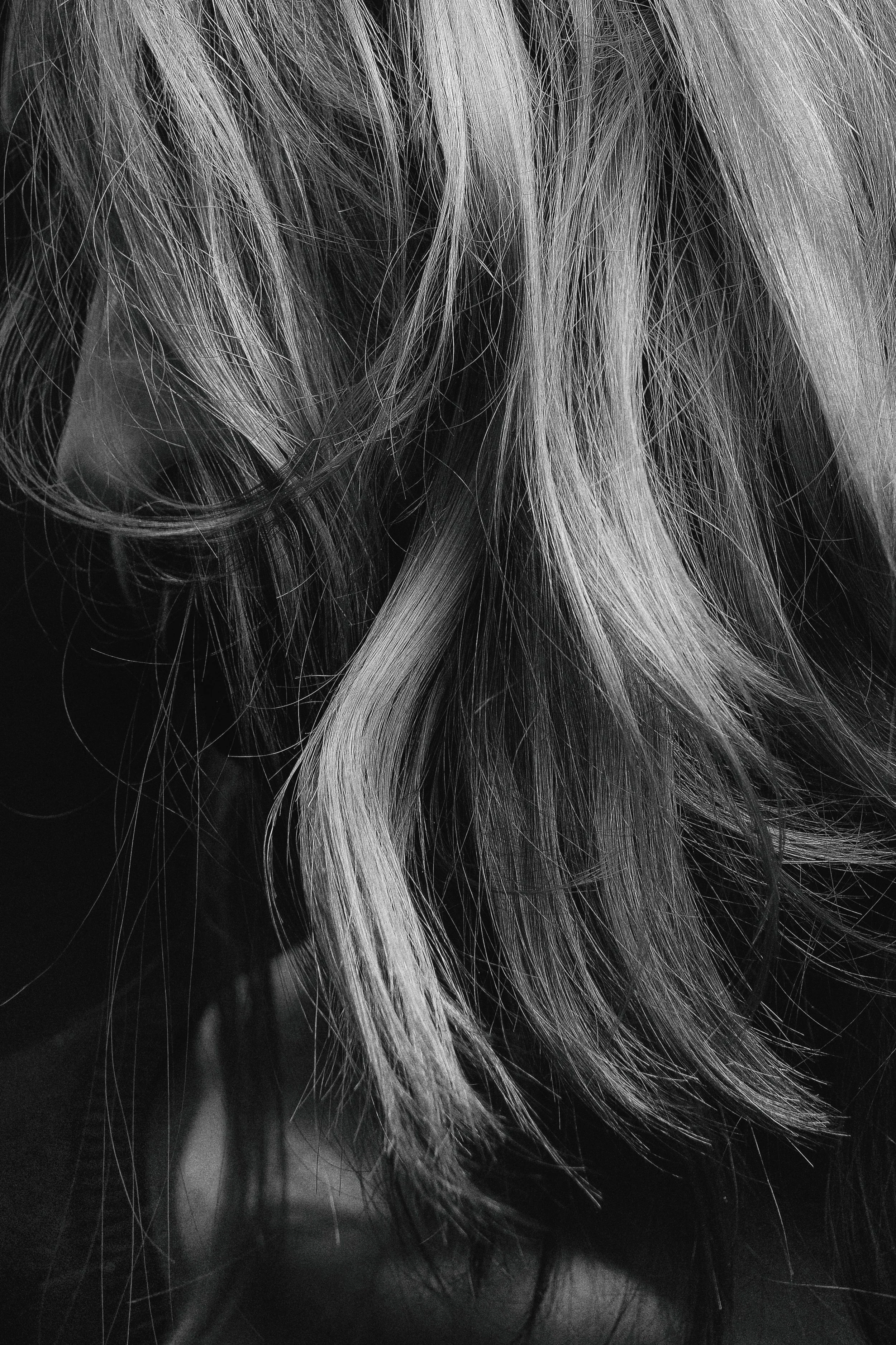 Close-up of light-colored hair strands against a dark background.