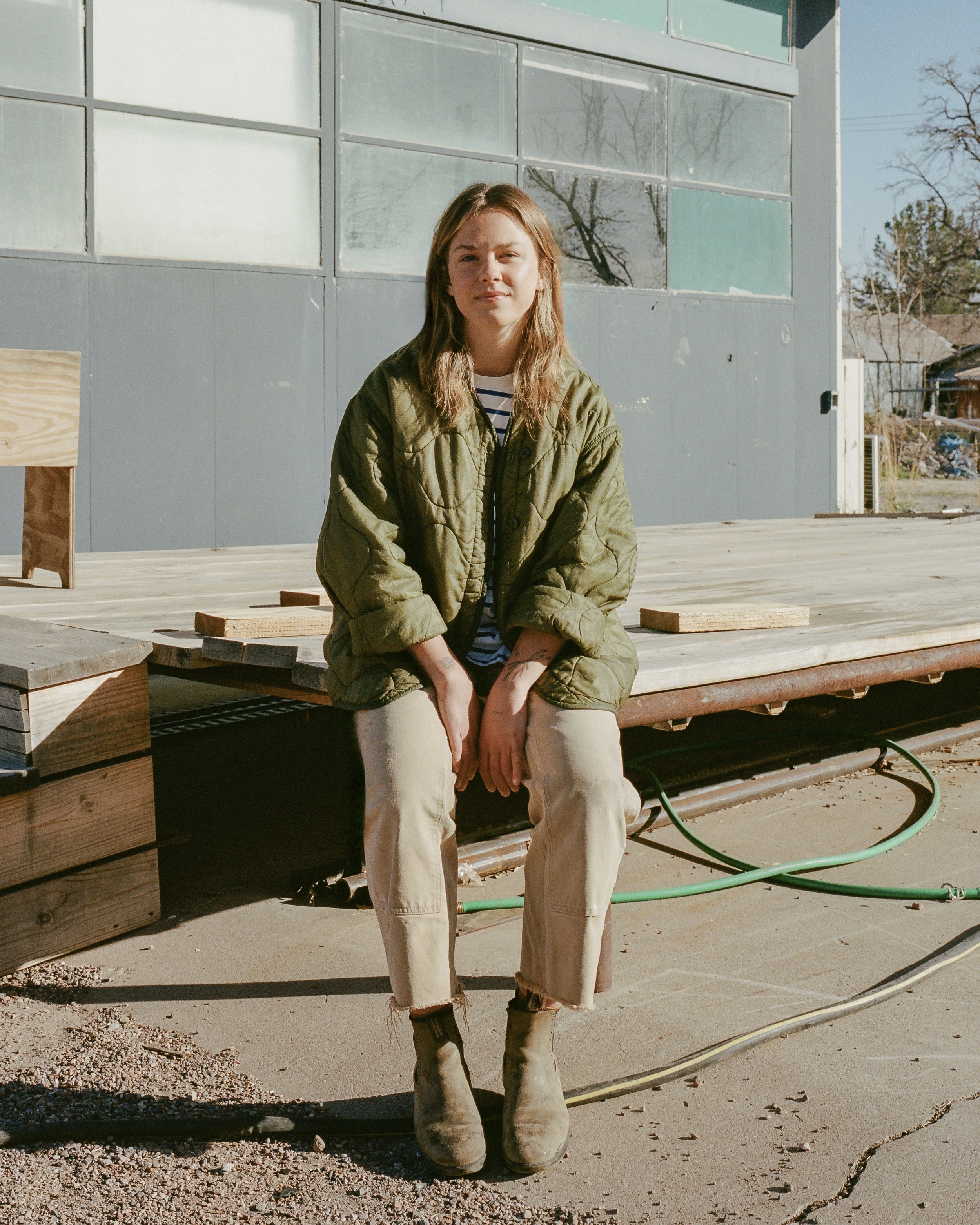 Woman sitting on a bench outside in a green coat