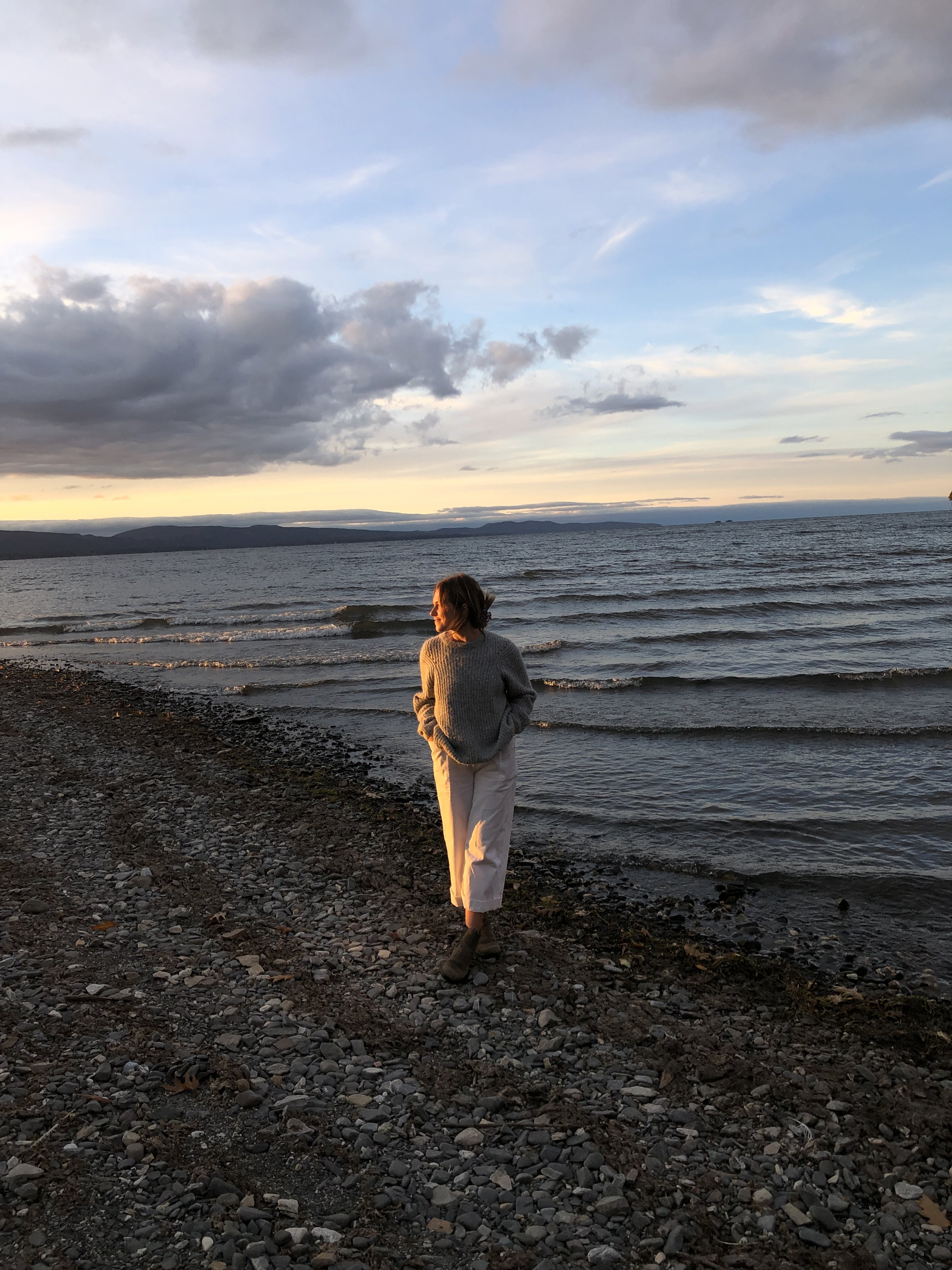 large beach with mountains and a girl standing on the beach