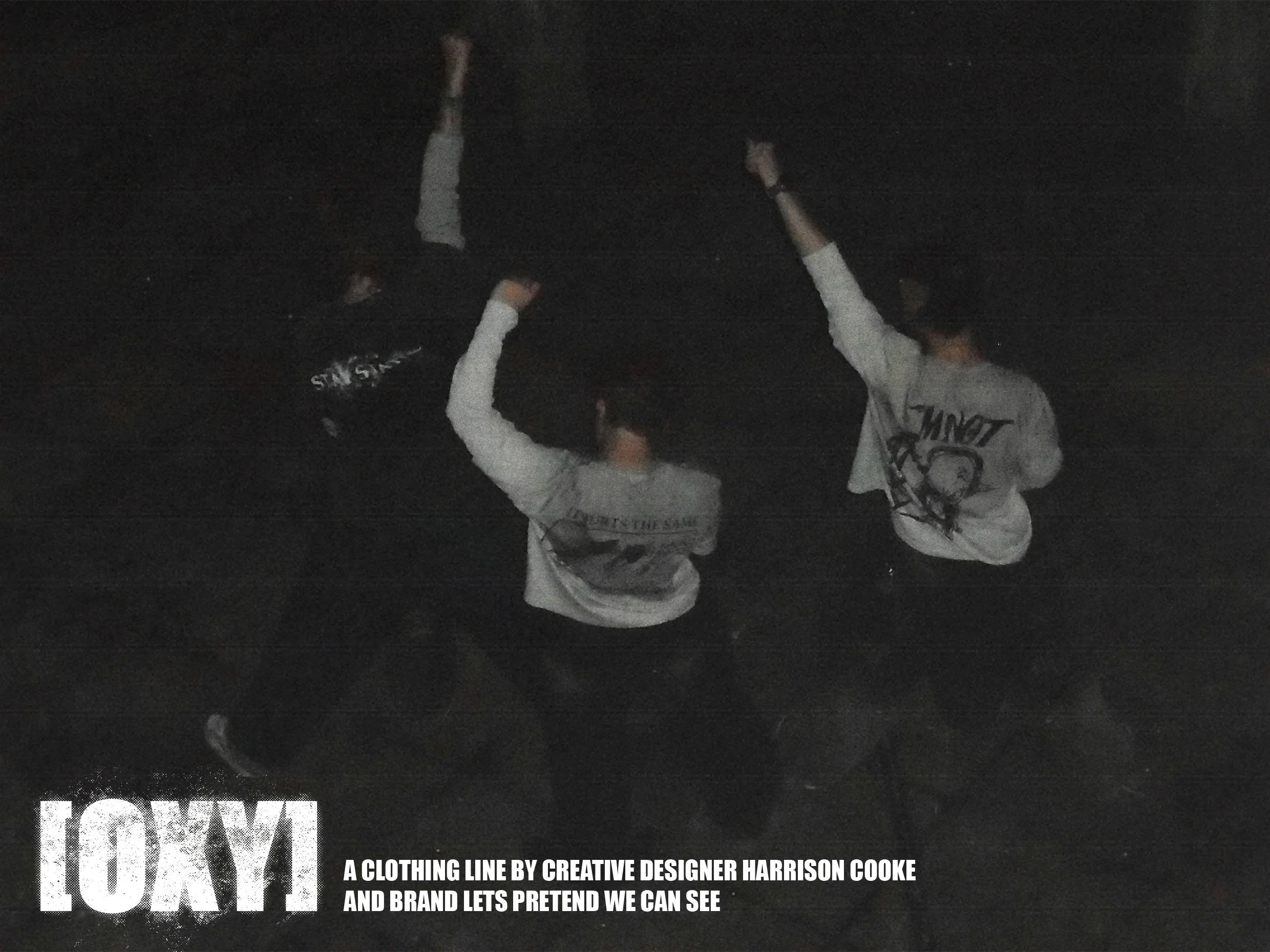 Two individuals wearing casual clothing standing outdoors at night, holding skateboards and raising their arms in celebration or excitement.