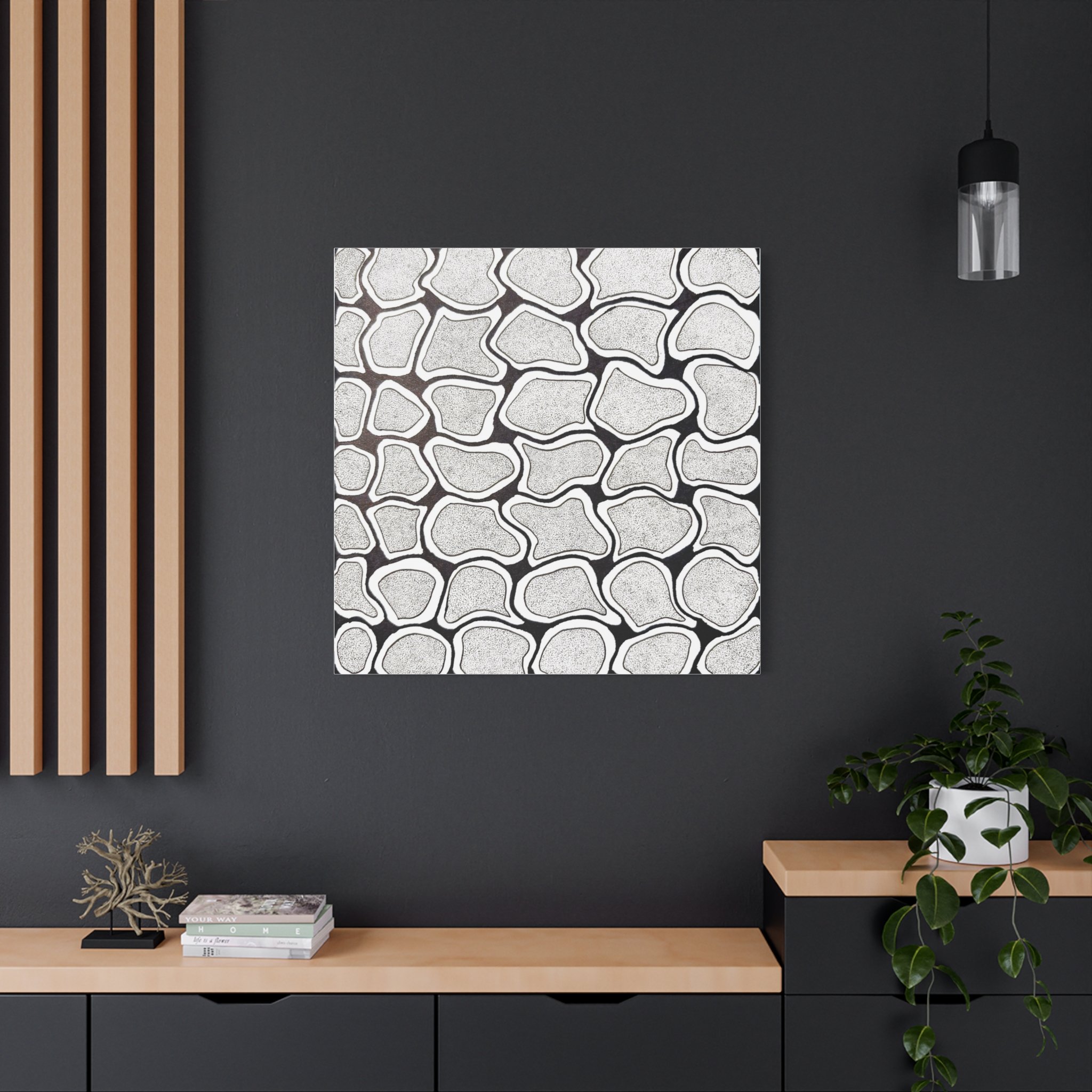 Interior of a modern room with dark gray walls, wooden slats on the left, a decorative wall art piece with a black and white abstract pattern, a black pendant light, a wooden console table with plants, books, and decorative items.