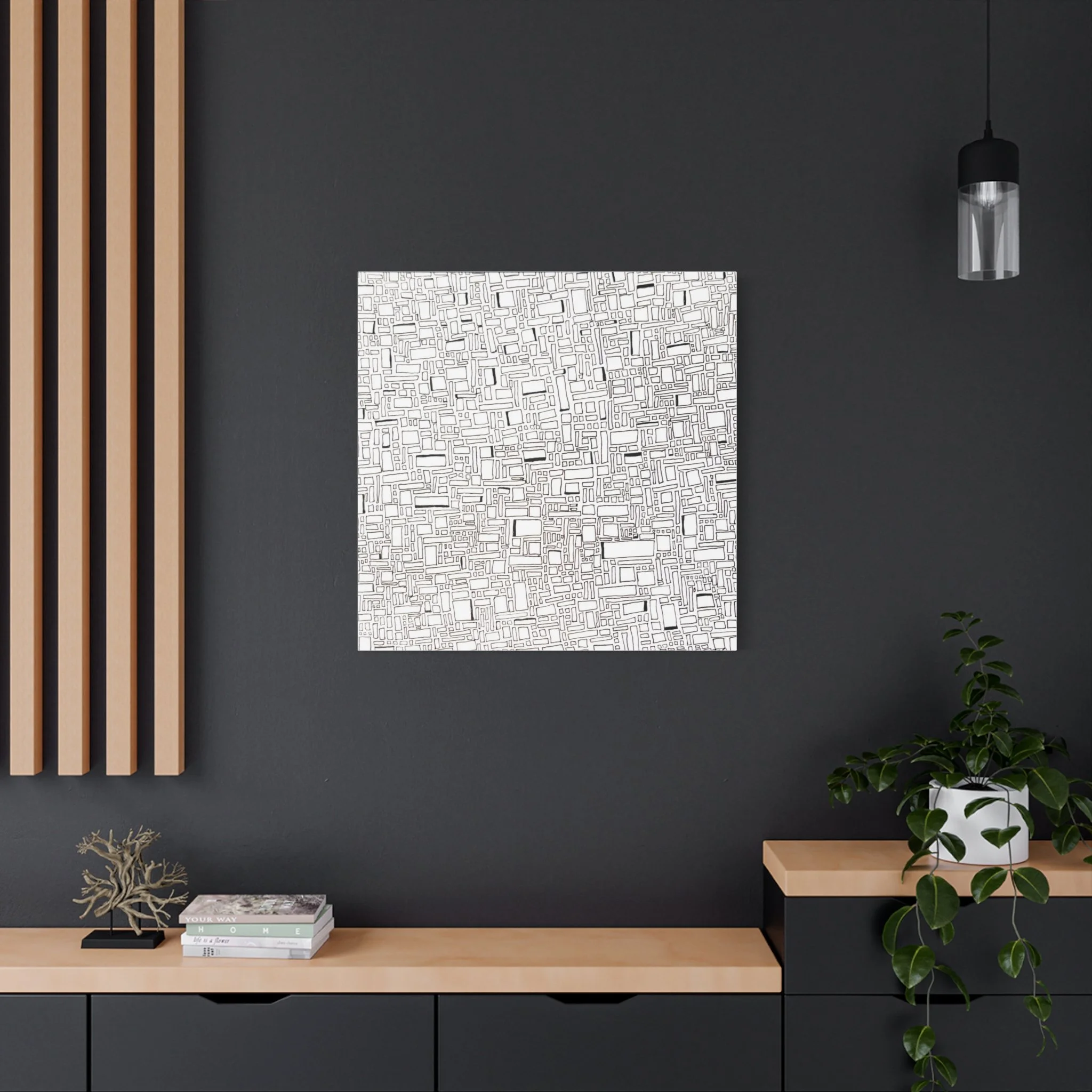 Modern interior wall decor with a white abstract line art panel hanging on a dark gray wall. Wooden slats on the left side and a hanging black and clear glass pendant light to the right. A light wooden console below holds books and decorative items, 