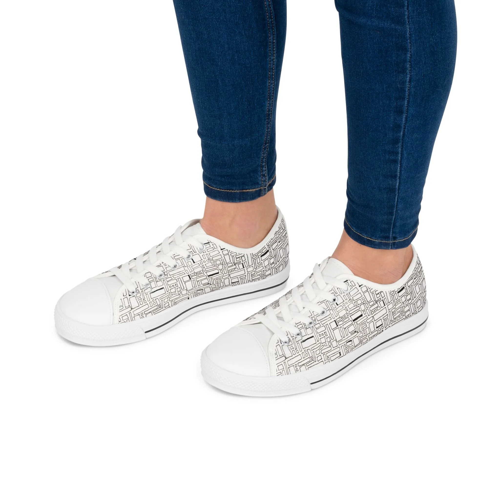Person wearing blue jeans and white sneakers with black geometric pattern.