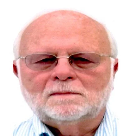 Close-up of an older man with a white beard, wearing glasses and a striped shirt.