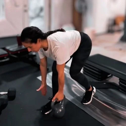 Woman strength training with a kettlebell during a home workout