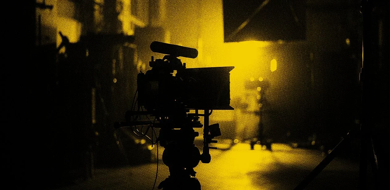 A camera on a tripod in a dimly lit room with yellow lighting.