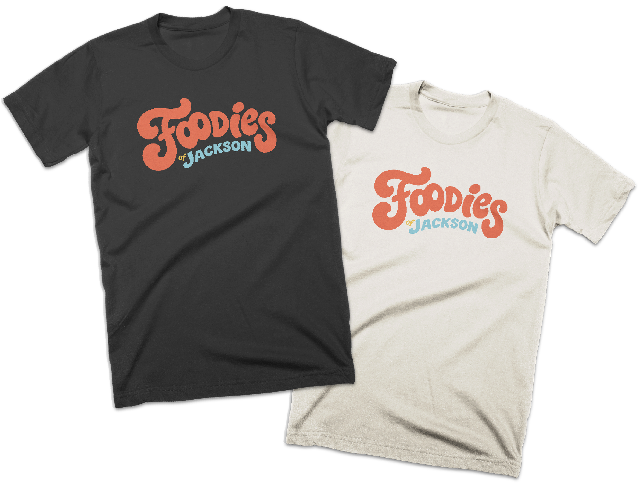 Two T-shirts with the phrase 'Foodies of Jackson' in large orange and light blue letters, one black and one beige.