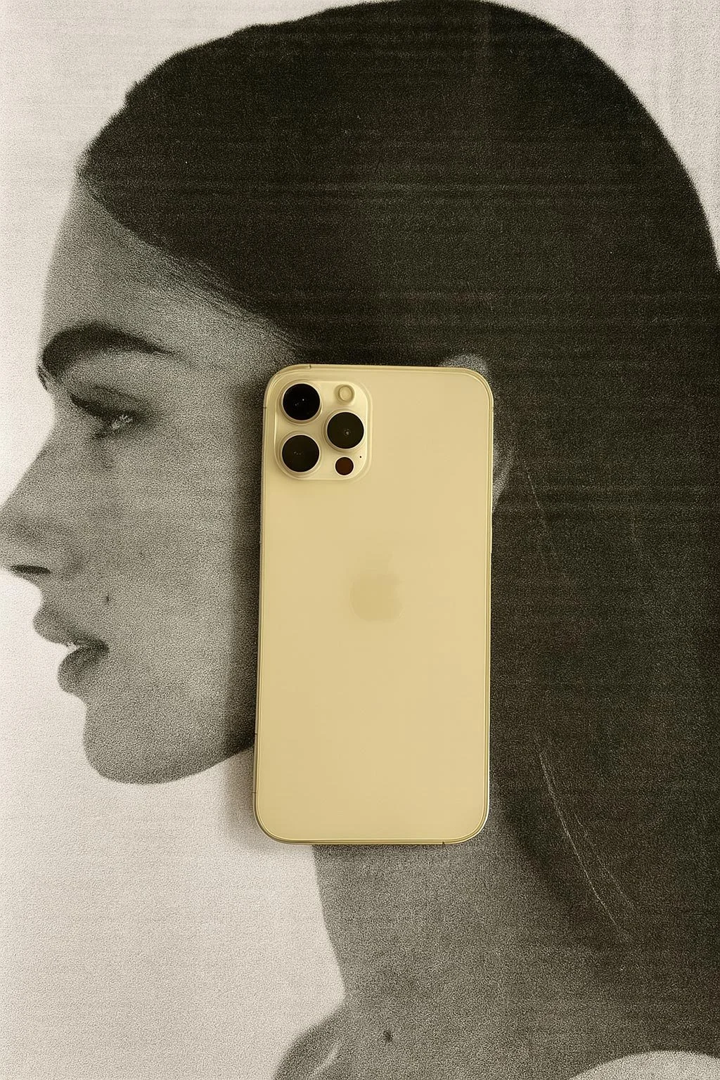 A yellow iPhone placed on top of a black-and-white photo of a woman's profile with dark hair and makeup.