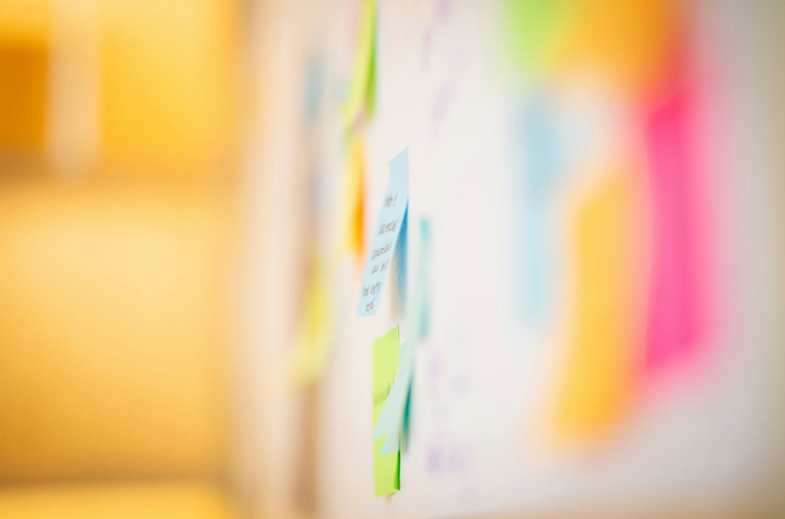 Colorful wall with sticky notes and papers attached, used for planning or brainstorming.