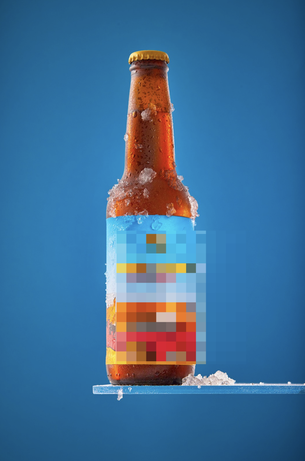 A cold glass bottle of beer with condensation and ice on it, standing on a clear surface against a blue background.