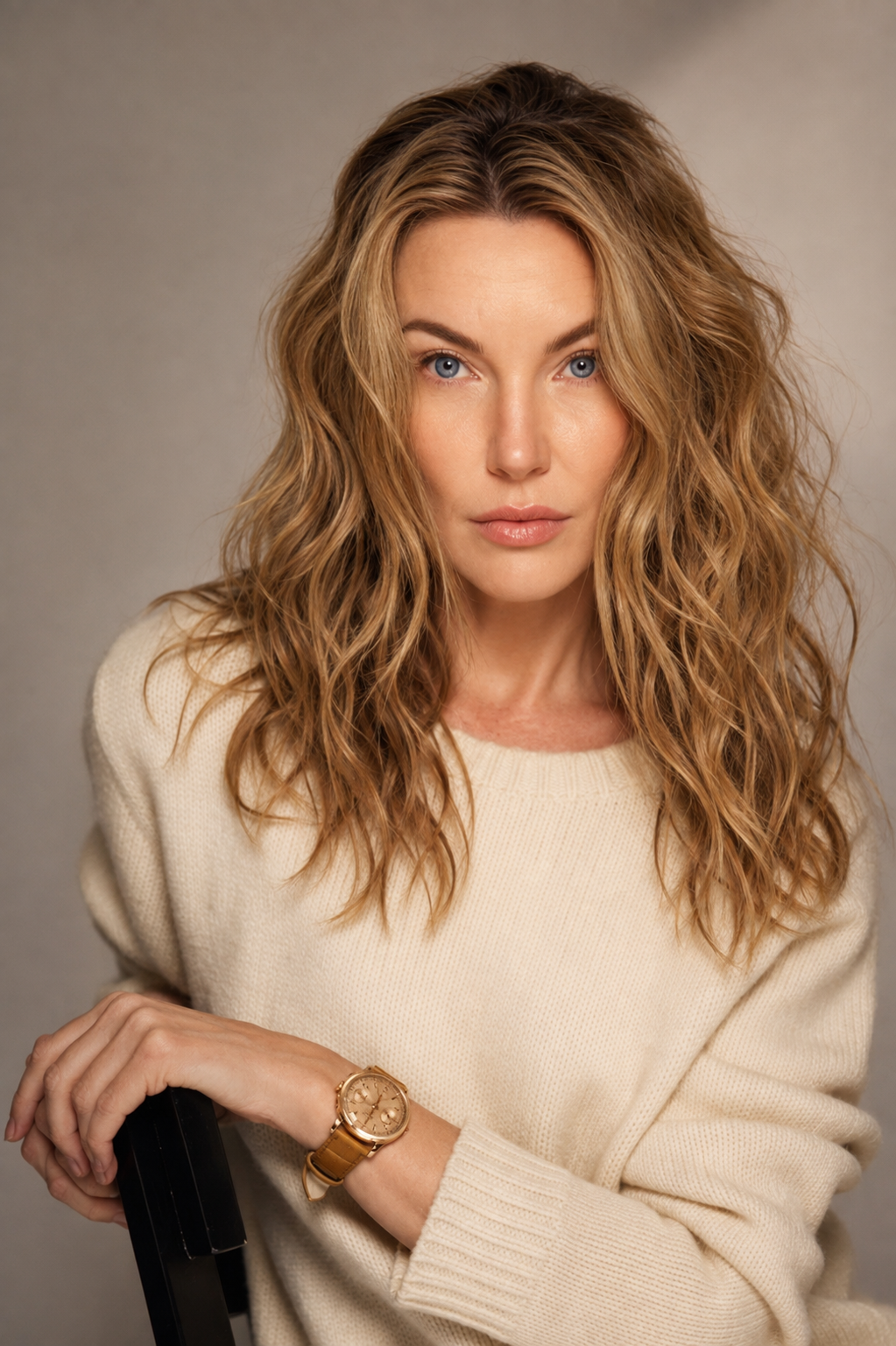 Portrait of Dr. Linda Ellison with long, wavy, dark blonde hair and blue eyes wearing a cream sweater and a gold watch, sitting and looking at the camera.